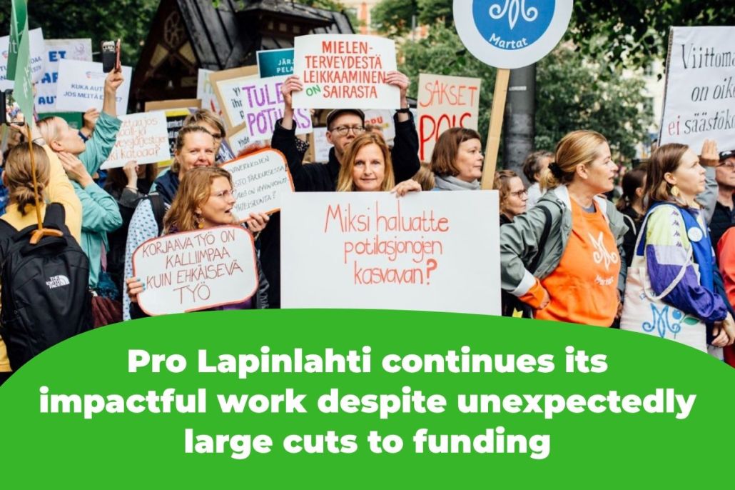 The picture shows protesters holding signs that read, among other things, "Why do you want patient queues to grow?" and "Corrective work is more expensive than preventive work" and "Cutting mental health services is sick."