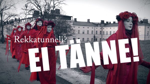 Punaisiin kaapuihin pukeutuneet naiset kulkevat jonossa Lapinlahden puistossa. Kuvan päällä on teksti "Satamatunneli? Ei tänne"