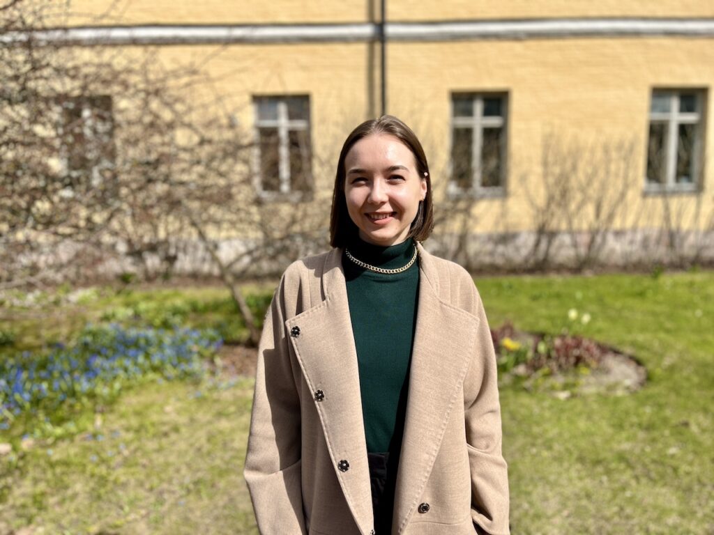 Kuvassa nainen Lapinlahden sairaalarakennuksen edustalla vaaleassa takissa.