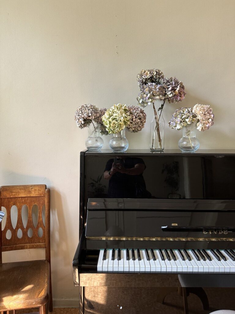Kuvassa piano ja kukkia.