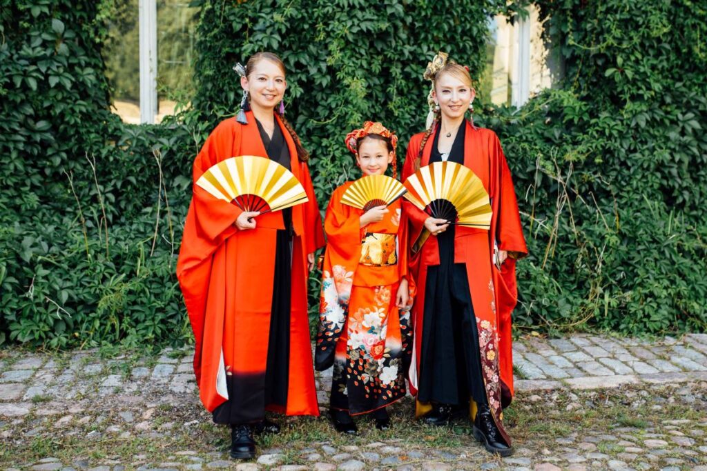 Japanilaistaiteiljat punaisissa asuissaan etupihalla.